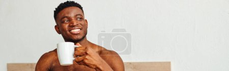 Photo for Handsome shirtless african american man with coffee cup smiling and looking away in bedroom, banner - Royalty Free Image