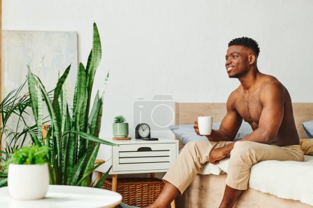 Photo for Smiling shirtless african american man with coffee cup sitting near green potted plants in bedroom - Royalty Free Image