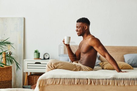 Photo for Side view of happy african american shirtless man in pajama pants sitting with coffee cup in bedroom - Royalty Free Image