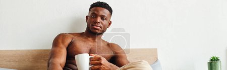 Photo for Strong and handsome african american man with coffee cup looking at camera in bedroom, banner - Royalty Free Image