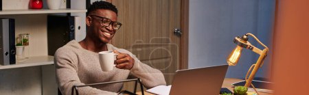 positivo afroamericano freelancer con café sonriendo durante el chat de vídeo en casa oficina, pancarta