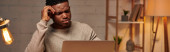serious african american freelancer working at laptop in home office at night, horizontal banner mug #692608302