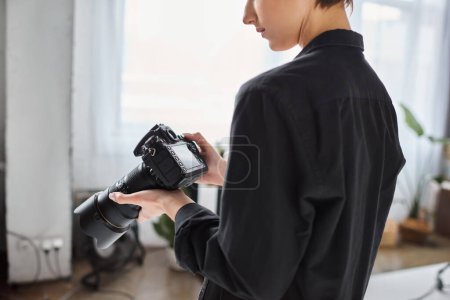 abgeschnittene Ansicht einer Fotografin in Alltagskleidung, die im Studio mit verschiedenen Geräten arbeitet