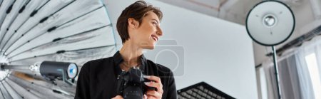 Photo for Jolly female photographer in casual clothes with camera in hands smiling and looking away, banner - Royalty Free Image