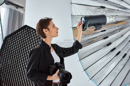 attractive young female photographer in everyday clothing setting her equipment in her studio