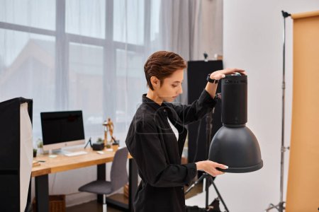 attraktive brünette Frau mit kurzen Haaren beim Betrachten ihrer Fotoausrüstung in ihrem Studio