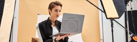 pretty short haired photographer sitting and retouching photos in studio using her laptop, banner