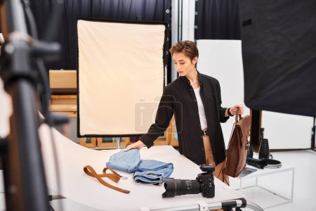 gut aussehende junge Fotografin bereitet sich auf Fotos von Jeans und braunem Rucksack vor