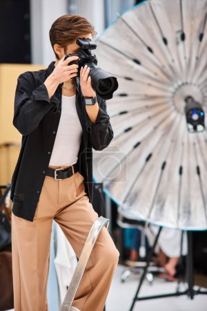 Foto de Atractiva mujer de pelo corto en traje casual tomar fotos con su cámara moderna en su estudio - Imagen libre de derechos