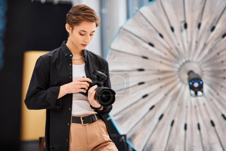 attraktive junge Frau in lässiger Kleidung beim Fotografieren mit ihrer modernen Kamera in ihrem Atelier