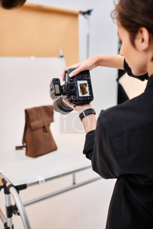 Foto de Encantadora fotógrafa de pelo corto tomando fotos de mochila de cuero marrón en su estudio - Imagen libre de derechos