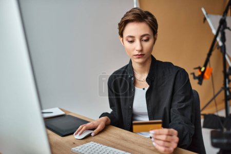 atractiva joven fotógrafa con atuendo casual y cómodo pagando en línea con su tarjeta de crédito