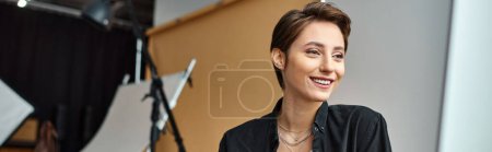 jeune femme gaie attrayante avec des accessoires souriant joyeusement à son studio photo, bannière