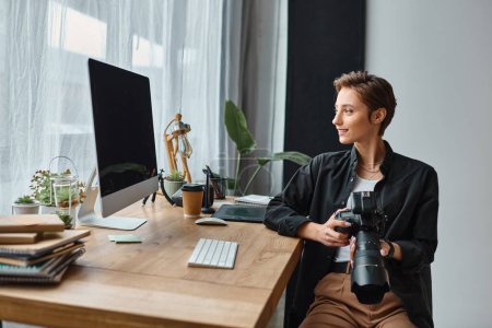 Photo for Cheerful attractive female photographer in casual attire working hard on her photos in studio - Royalty Free Image
