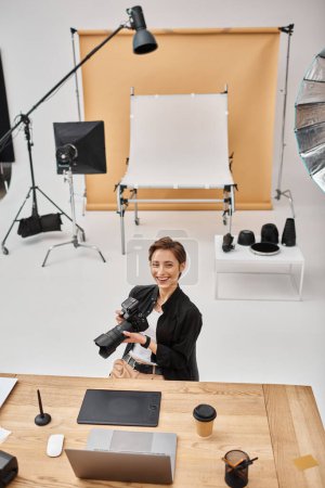 cheerful professional woman in casual attire smiling at camera working at her workplace in studio