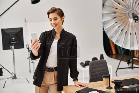 jolly pretty female photographer in casual attire making stories for her social media in her studio
