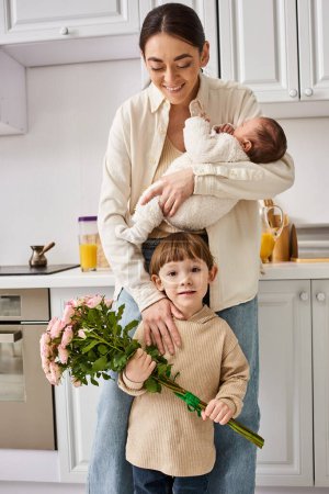 famille gaie attentionnée en tenue de maison posant avec bouquet de fleurs tout en cuisine, parentalité moderne