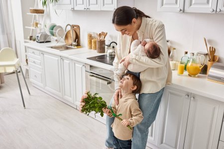 famille joyeuse attentionnée en tenue de maison posant avec bouquet de fleurs tout en cuisine, parentalité moderne