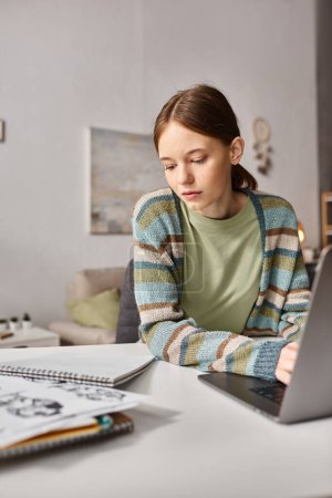 Téléchargez les photos : Adolescente engagée dans l'apprentissage en ligne avec son ordinateur portable et son ordinateur portable dans un cadre confortable à la maison, à l'ère numérique - en image libre de droit