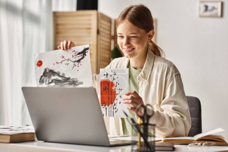 glücklich Teenager Mädchen zeigt ihre Kunstwerke während des Studiums und Blick auf ihren Laptop, Kunstunterricht online