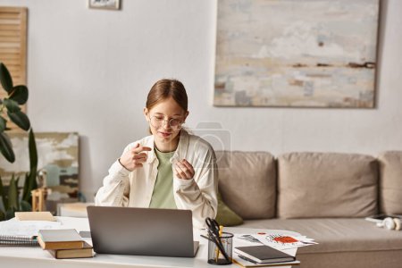 cheerful teen girl gesturing during video call and online class at home,  e-learning concept