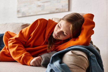 depressives Mädchen auf Sofa im Wohnzimmer liegend, Einsamkeit und Melancholie des Teenager-Konzepts