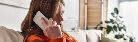 Photo for Sad girl having phone call on smartphone and sitting on sofa in living room, teenage problems banner - Royalty Free Image