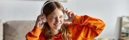 Jovencita alegre en auriculares blancos inalámbricos disfrutando de la música en casa, pancarta horizontal