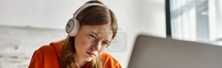 Téléchargez les photos : Jeune adolescente concentrée dans les écouteurs sans fil e-learning avec ordinateur portable à la maison, bannière horizontale - en image libre de droit