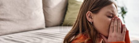 Photo for Teenage girl in distress, covering face with hands while crying near couch in living room, banner - Royalty Free Image