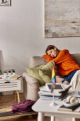 melancholic teen girl in hoodie sits on couch with a distant look, blurred lgbtq flag on foreground magic mug #692877336