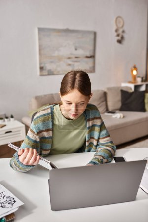 Photo for Focused teen girl with notebook e-learning with laptop near sketches and smartphone on desk - Royalty Free Image