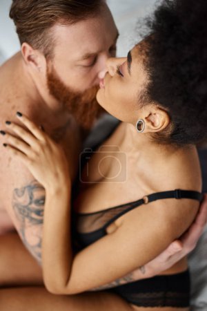 Téléchargez les photos : Vue de dessus du couple multiculturel sexy embrassant et embrassant dans la chambre, séduction et passion - en image libre de droit