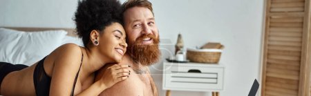 banner of bearded man and african american woman, interracial couple lying on bed and watching movie