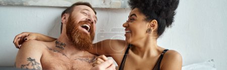 glücklicher und tätowierter Mann ohne Hemd lachend mit lockiger afrikanisch-amerikanischer Freundin, Banner