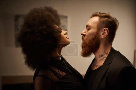 curly african american woman in chic dress seducing tattooed boyfriend with beard, date night