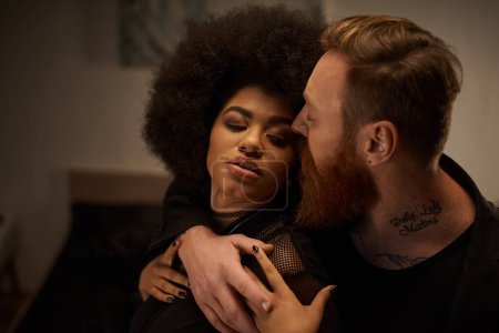 hombre tatuado con barba seducir rizado africana americana mujer en vestido en la noche de la cita, sexy pareja