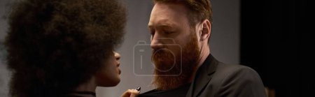 curly african american woman in dress pulling blazer of bearded man during date, sexy couple banner