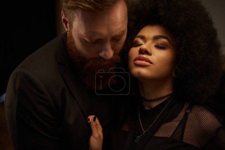 curly african american woman in dress pulling blazer of bearded boyfriend during date, sexy couple