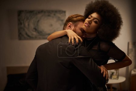 bärtiger Mann verführt junge Afroamerikanerin mit lockigem Haar, intimer Moment eines sexy Paares