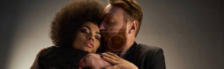 bearded man kissing african american woman with curly hair, intimate moment of sexy couple banner