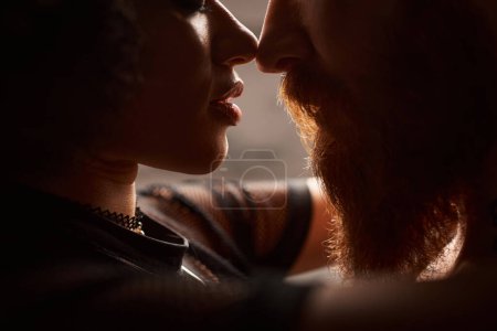 close up of african american woman with curly hair seducing bearded man with red hair, sexy couple