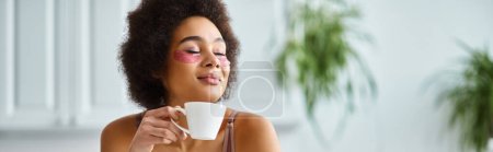 mujer afroamericana feliz con parches para los ojos de pie en lencería y disfrutando del café, pancarta