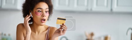 Banner einer überraschten schwarzen Frau mit Kopfhörern und Flecken unter den Augen, die auf die Kreditkarte schaut
