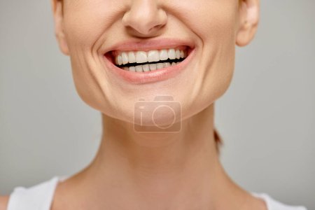 Téléchargez les photos : Vue recadrée de femme excitée exsudant sourire joyeux et sain sur fond gris, dents blanches - en image libre de droit
