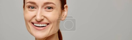 Téléchargez les photos : Contenu et rousse femme en débardeur blanc avec un sourire tendre et sain sur fond gris, bannière - en image libre de droit