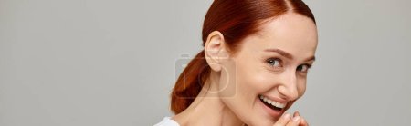 Téléchargez les photos : Femme étonnée et rousse en débardeur blanc riant un fond gris, éclatante bannière sourire - en image libre de droit