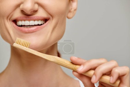 Téléchargez les photos : Plan recadré de femme heureuse dans les années 30 avec des dents blanches saines tenant une brosse à dents en bambou, soins dentaires - en image libre de droit