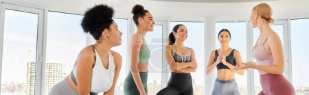 group of happy diverse women in leggings and crop tops practicing pilates with trainer, banner