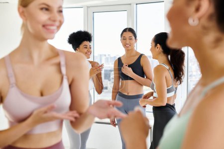 focus on female friends in sportswear chatting while standing in sportswear before pilates class